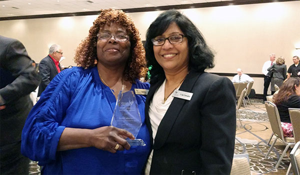 Charlotte "Sista C" Ferrell receiving a University of Phoenix "Faculty of the Year" award from Dr. Rada